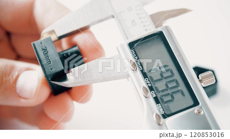 Engineer measures 3D printed sample with an electronic caliper or calliper. Metrology or quality control related close-up shot 120853016