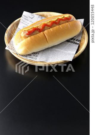 ケチャップとマスタードがかかったホットドックを黒背景で撮影 120855448