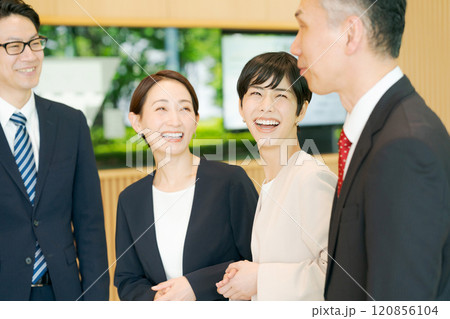 オフィスで話す笑顔のビジネスマン達 オフィスで話す笑顔のビジネスマン達 120856104