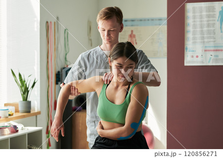 Assisting Woman in Physical Therapy Session with Focus Assisting Woman in Physical Therapy Session with Focus 120856271