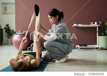Physical Therapist Assisting Woman with Stretching Exercise Physical Therapist Assisting Woman with Stretching Exercise 120856585