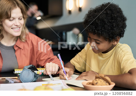 Smiling Female Teacher Helping Boy with Homework 120856882
