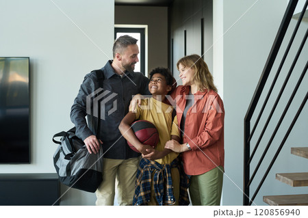 Smiling Family Greeting with Basketball at Home Doorway 120856940