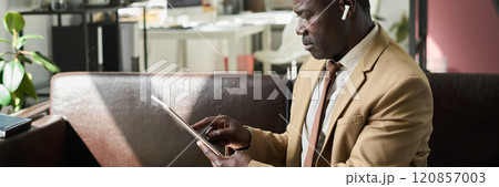 Mature man pointing at tablet screen 120857003