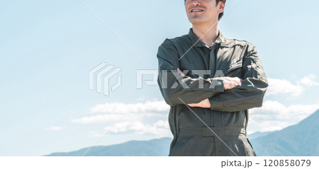 青空の下にいる作業着姿で腕組みをする中年アジア人男性（就農者・農家・農業・後継者） 120858079