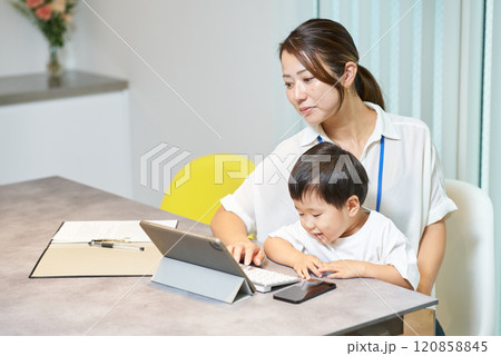 子供を抱えて仕事をする女性 120858845