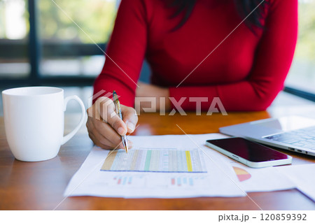 Woman holding a pen while working at office. Close up shot hands of woman use pen to analyze graphs and business data. Businesswomen working about new startup on laptop to analysis finance of project. 120859392