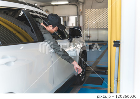 自動車整備工場の構内で車両を動かす自動車整備士の男性 自動車整備工場の構内で車両を動かす自動車整備士の男性 120860030