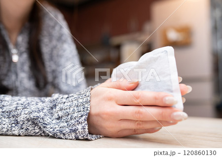 使い捨てカイロを持つ女性の手元 120860130