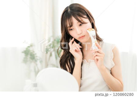 美顔器でマッサージしながらお肌に悩む若いアジア人女性(スキンケア) 120860280