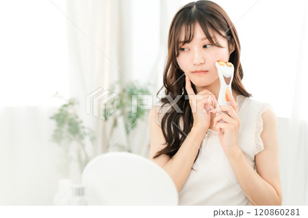 美顔器でマッサージしながらお肌に悩む若いアジア人女性(スキンケア) 120860281