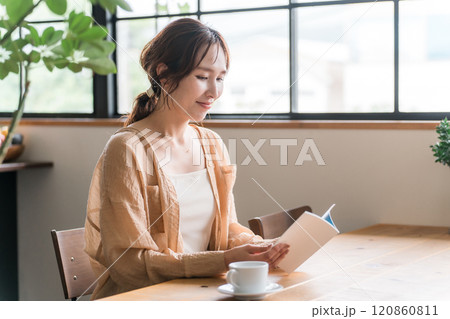 カフェでコーヒーを飲みながら読書をする女性 120860811