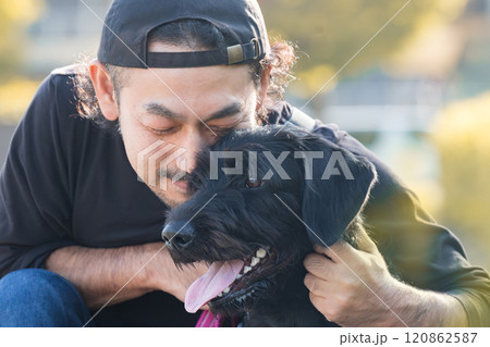 紅葉や秋の葉が場所でペットの大型犬と寄り添う仲良しな飼い主の男性のクローズアップ 紅葉や秋の葉が場所でペットの大型犬と寄り添う仲良しな飼い主の男性のクローズアップ 120862587