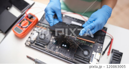 Gloved hands hold a laptop microcircuit, close-up Gloved hands hold a laptop microcircuit, close-up 120863005
