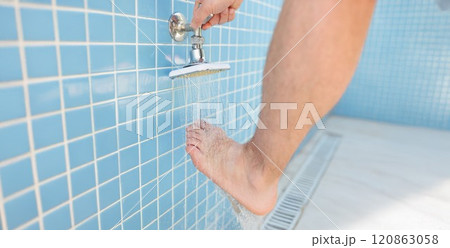 A man regulates the flow of water, washes foot in the shower 120863058