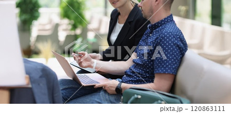 A man with a laptop and a woman with a tablet are talking 120863111