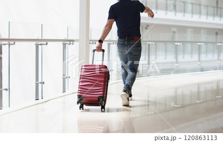 A man carrying a suitcase at the airport terminal A man carrying a suitcase at the airport terminal 120863113