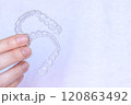 Hand holding Invisalign transparent braces on white background with copy space. Invisible retainers and aligners 120863492