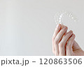 Hand holding Invisalign transparent braces on white background with copy space. Orthodontic invisible retainers and aligners 120863506