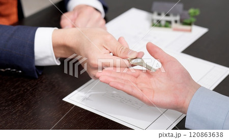 家の鍵を渡すビジネスマンの手元 120863638