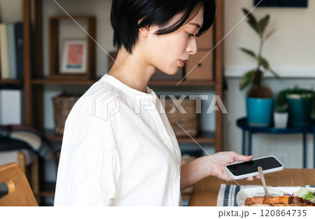 食事中にスマホを見る女性 120864735