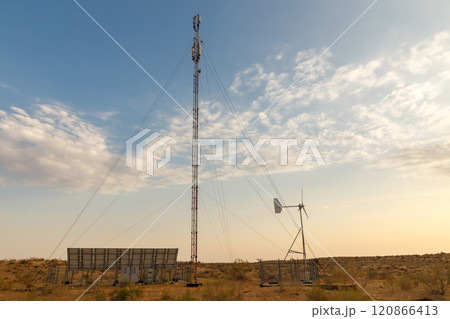 Cell tower integrating solar panels and wind turbine in Uzbekistan desert landscape 120866413