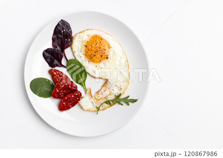 Fried egg, tomatoes and basil leaves on the plate. Fried egg, tomatoes and basil leaves on the plate. 120867986