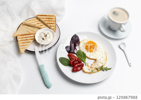 Fried egg on the plate, a cup of coffee and toasts with cheese sauce. 120867988