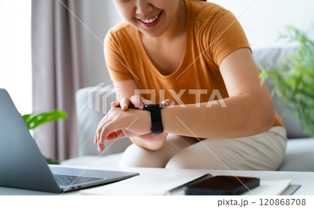 Happy young woman is using smartwatch on her wrist to check health data, notifications, set alarm. Happy young woman is using smartwatch on her wrist to check health data, notifications, set alarm. 120868708
