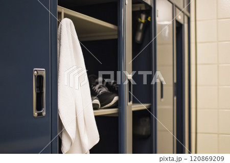 Open locker with towel and running shoes in gym changeroom 120869209