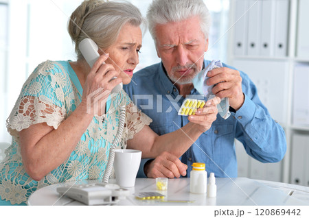 An elderly couple is sick and takes medication at home An elderly couple is sick and takes medication at home 120869442