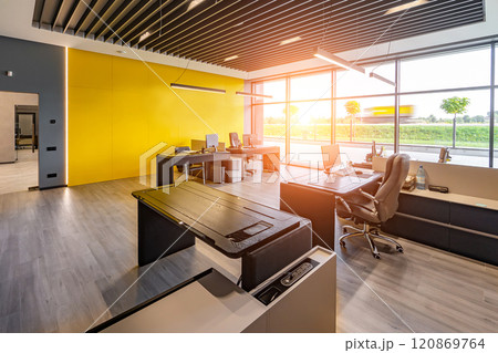 Modern office space with tables and chairs, computers and office supplies with no employees 120869764