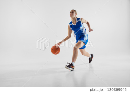 Dynamic image of teen girl in motion with ball, wearing blue uniform, competing for the victory, playing against white studio background Dynamic image of teen girl in motion with ball, wearing blue uniform, competing for the victory, playing against white studio background 120869943