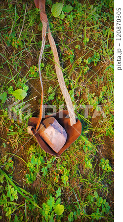 An antique leather sling lies on the ground An antique leather sling lies on the ground 120870305