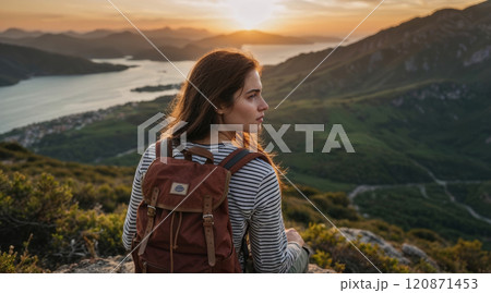 young woman with a backpack resting on a mountaintop 120871453
