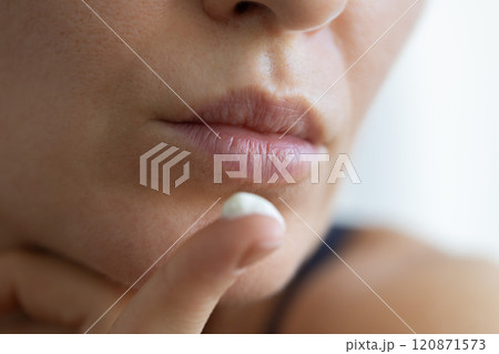 Woman with cream for lips on her finger. Closeup, selective focus. 120871573