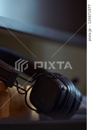 Stylish black headphones resting on a wooden desk 120871977