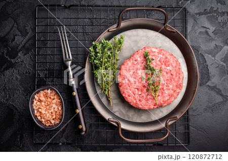 Stack of Raw meat patties, cutlets, chopped meat for burgers in stell tray with herbs. black background. top view 120872712