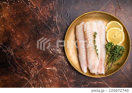 Raw cod loin pieces, whitefish fillets without skin on plate with herbs. brown background. top view 120872740