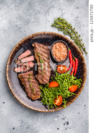 BBQ Grilled skirt or machete Steak, beef meat on a plate with salad. grey background. top view BBQ Grilled skirt or machete Steak, beef meat on a plate with salad. grey background. top view 120872780