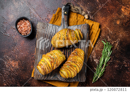 Roasted Hasselback Potato with Fresh thyme and rosemary. Dark background. Top view Roasted Hasselback Potato with Fresh thyme and rosemary. Dark background. Top view 120872811