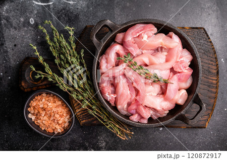 Raw Chicken sliced thighs fillets in a skillet. black background. top view Raw Chicken sliced thighs fillets in a skillet. black background. top view 120872917
