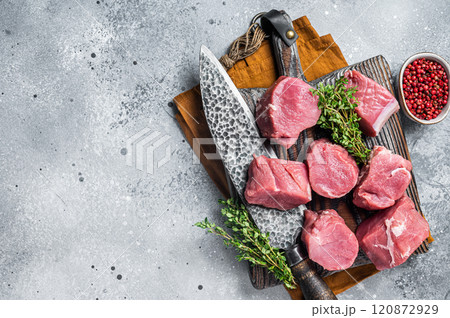 Fresh Raw pork tenderloin medallions steaks on a wooden cutting board. Gray background. Top view. Copy space Fresh Raw pork tenderloin medallions steaks on a wooden cutting board. Gray background. Top view. Copy space 120872929