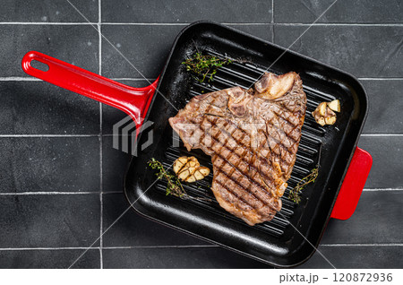 Grilled T-bone, t bone beef meat Steak on a grill skillet. Black background. Top view Grilled T-bone, t bone beef meat Steak on a grill skillet. Black background. Top view 120872936