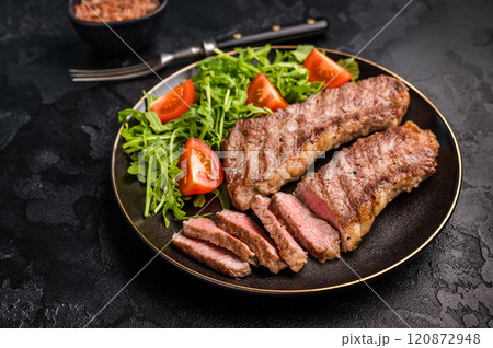 Grilled Steak from Black Angus beef meat on a plate with salad. black background. top view 120872948