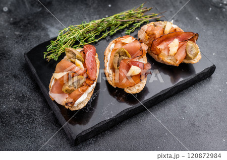 Prosciutto and pesto bruschetta, parmesan cheese and olives. black background. top view 120872984