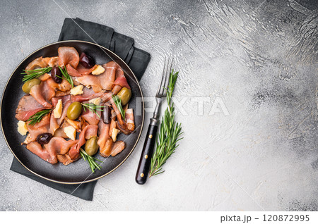 Antipasto with Prosciutto ham, parmesan cheese, rosemary and olives in a plate. grey background. top view 120872995