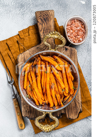 Roasted sweet potato french fries in a skillet with herbs. White background. Top view 120873005