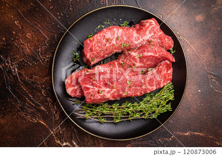 Tri tip steaks, Raw marbled beef meat on plate with herbs. brown background. top view 120873006