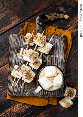 Roasted Marshmallow on the sticks with Cup of coffee on wooden board. Wooden background. Top view 120873056